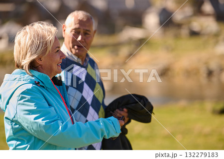 Elderly couple strolling through the breathtaking beauty of nature, maintaining their vitality and serenity, embracing the joys of a health-conscious and harmonious lifestyle Elderly couple strolling through the breathtaking beauty of nature, maintaining their vitality and serenity, embracing the joys of a health-conscious and harmonious lifestyle 132279183