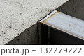 A rough-textured concrete column and a dark, raw steel I-beam. 132279222