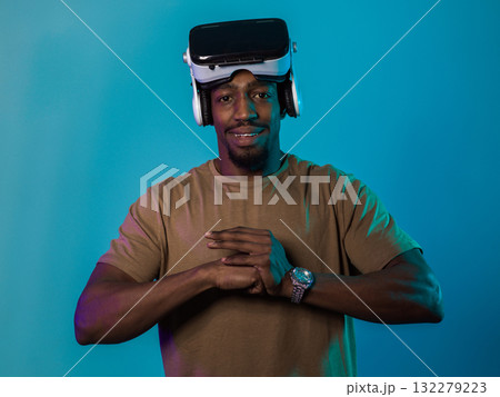 In an avant-garde scene, an African American man engages in cutting-edge virtual reality gaming, utilizing VR glasses to immerse himself in futuristic boxing games, set against a vivid blue background 132279223