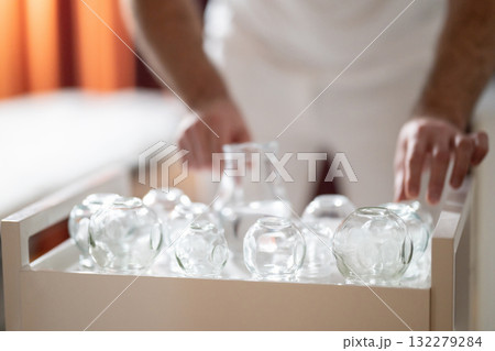 Therapist Preparing Glass Cups for Traditional Cupping Therapy. Close up of therapists hands arranging clean glass cups on a tray before starting a traditional cupping therapy session. 132279284
