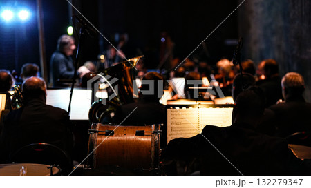 Orchestra rehearsal with cello in focus and musicians in soft bokeh background 132279347