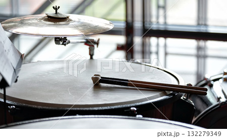 Drum kit with cymbal and drumsticks in bright rehearsal space 132279349