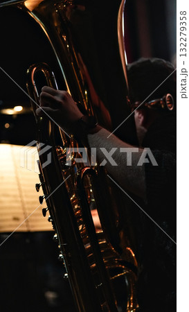 Musician playing tuba in dramatic golden light and dark background 132279358
