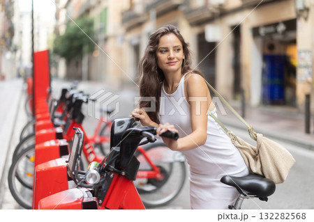 Young woman rents an electric bike on street Young woman rents an electric bike on street 132282568