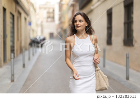 Young woman walks along city street 132282613