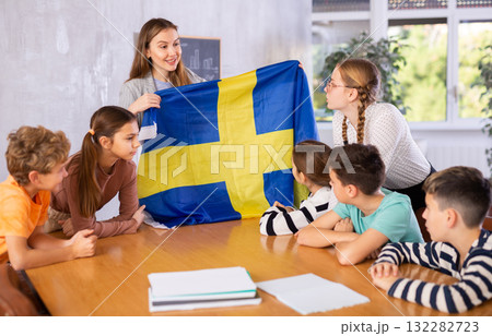 Teacher showing Sweden flag to group of schoolchildren 132282723