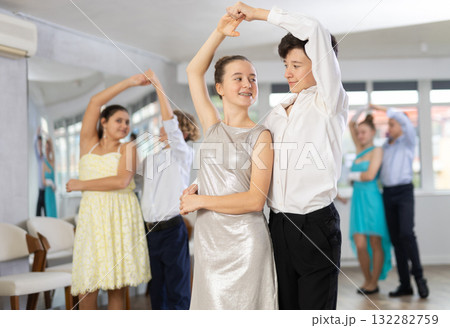 Positive teen boy and girl are dancing classic version of waltz in couple during lesson at studio Positive teen boy and girl are dancing classic version of waltz in couple during lesson at studio 132282759