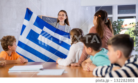 Teacher showing Greece flag to group of schoolchildren 132282808