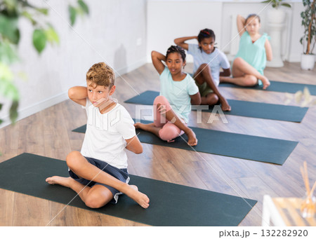 Portrait of children practicing Lord of Fishes Pose during group yoga training 132282920