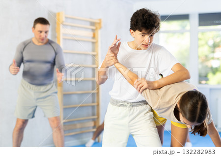 Preteen children pairs learning strength self-defense in gym 132282983