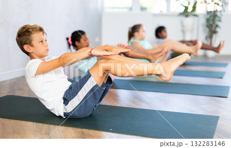 School kids training yoga on yoga mat in gym. 132283146
