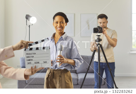 Filming interview or media content in studio, smiling woman holding microphone looking at camera 132283262