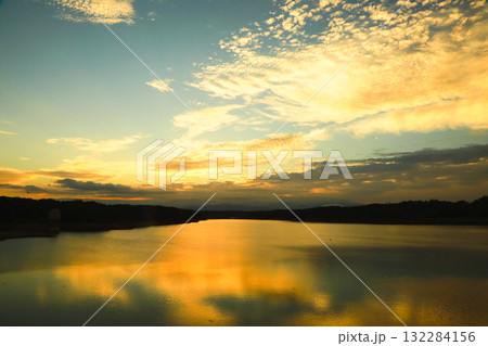 黄金色に輝く多摩湖（村山上貯水池）の夕焼けと水鏡 132284156