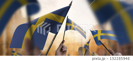 Sweden flags in their hands on a blurred urban background Sweden flags in their hands on a blurred urban background 132285948