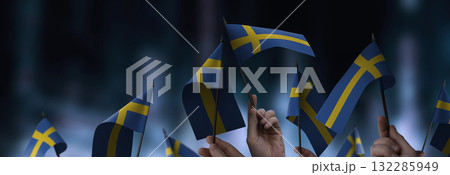 Sweden flags in their hands on a blurred urban background Sweden flags in their hands on a blurred urban background 132285949