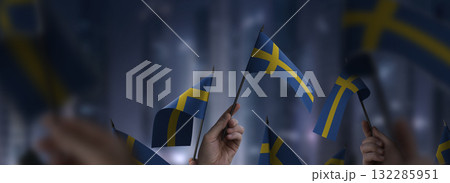 Sweden flags in their hands on a blurred urban background Sweden flags in their hands on a blurred urban background 132285951
