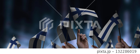 Finland flags in their hands on a blurred urban background 132286019