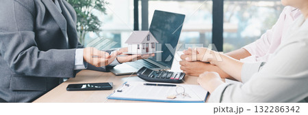 Mortgage consultation panorama with miniature house model in hand, financial advisor meeting clients, property investment, home loan agreement, real estate planning and housing business negotiation. Mortgage consultation panorama with miniature house model in hand, financial advisor meeting clients, property investment, home loan agreement, real estate planning and housing business negotiation. 132286342