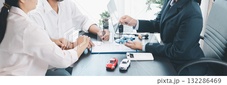 Panorama view of car dealer handing key and vehicle model to customer during contract signing, concept of auto loan, finance, leasing, insurance, purchase agreement and business success. auto loan. Panorama view of car dealer handing key and vehicle model to customer during contract signing, concept of auto loan, finance, leasing, insurance, purchase agreement and business success. auto loan. 132286469