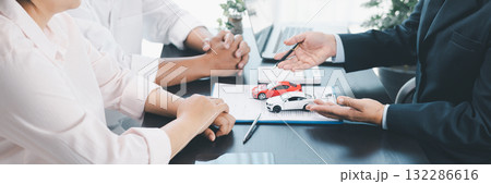Panorama view of car loan agreement signing with dealer presenting vehicle model, customer using calculator at office desk, concept of auto finance, leasing, insurance and business contract. Panorama view of car loan agreement signing with dealer presenting vehicle model, customer using calculator at office desk, concept of auto finance, leasing, insurance and business contract. 132286616
