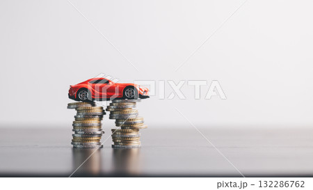 Red car model on stacked coins, symbolizing auto loan, car finance, investment, insurance and savings concept on a clean minimal background. car finance, investment, insurance Red car model on stacked coins, symbolizing auto loan, car finance, investment, insurance and savings concept on a clean minimal background. car finance, investment, insurance 132286762