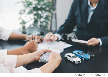 Businessman explaining car loan agreement with calculator, customer discussing auto finance deal at office desk with toy car and document, concept of vehicle loan, insurance or car leasing. car loan. 132286763