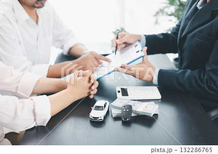 Car loan officer explaining contract details to customer with cash, calculator, key and toy car on table, concept of auto finance, leasing, insurance, payment plan and business agreement. car loan. 132286765