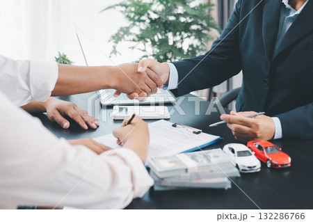 Business handshake after signing car loan contract, symbol of trust and successful auto finance agreement with money, calculator and vehicle model on desk, concept of deal and partnership. car loan. Business handshake after signing car loan contract, symbol of trust and successful auto finance agreement with money, calculator and vehicle model on desk, concept of deal and partnership. car loan. 132286766