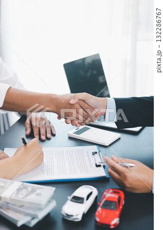 Business handshake after signing car loan contract, symbol of trust and successful auto finance agreement with money, calculator and vehicle model on desk, concept of deal and partnership. car loan. Business handshake after signing car loan contract, symbol of trust and successful auto finance agreement with money, calculator and vehicle model on desk, concept of deal and partnership. car loan. 132286767