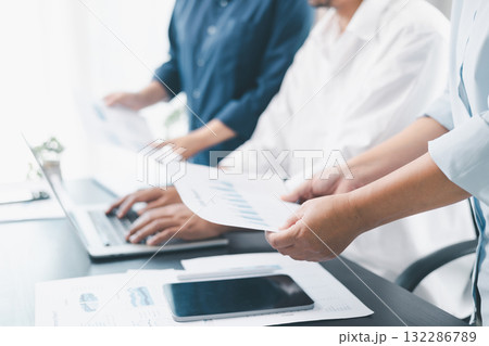 Business teamwork reviewing financial report with charts and graphs in modern office, colleagues discussing analysis, planning strategy, growth and corporate success with documents and technology. 132286789