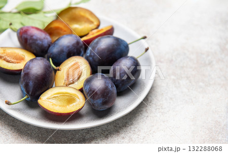 Fresh plums on plate showing halved fruit composition 132288068