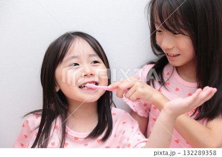 パジャマで歯磨きをする4歳と10歳の姉妹の女の子 パジャマで歯磨きをする4歳と10歳の姉妹の女の子 132289358