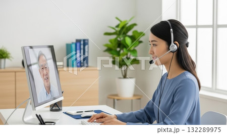 パソコン画面で高齢者とオンライン診療を行う女性医療スタッフ 132289975