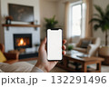 Hand holding a smartphone with a blank white screen in a softly living room 132291496