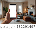 Hand holding a smartphone with a blank white screen in a softly living room 132291497