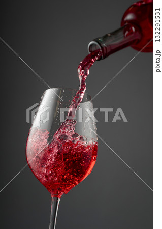 Pouring pink wine from a bottle into a glass. 132291531