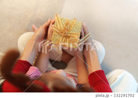 Gift Exchange. Close-up of mother and child holding a beautifully wrapped present. Gift Exchange. Close-up of mother and child holding a beautifully wrapped present. 132291702