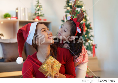 Christmas Celebration. A mother and daughter share a joyful moment with a gift. 132291703