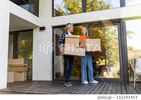 Senior man and woman transporting packed cardboard boxes into new house Senior man and woman transporting packed cardboard boxes into new house 132293453