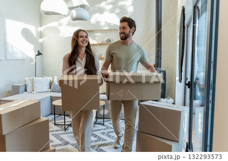 Two people with cardboard boxes entering a house and looking contented 132293573