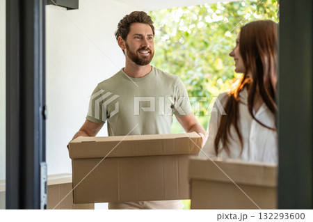 Young man and woman with cardboard boxes in hands entering the house 132293600