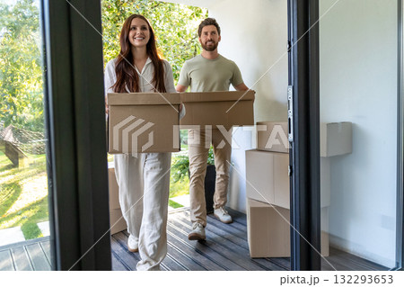 Young man and woman with cardboard boxes in hands entering the house Young man and woman with cardboard boxes in hands entering the house 132293653