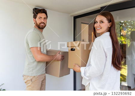 Caucasian couple holding boxes in hands while standing at the house entrance 132293692
