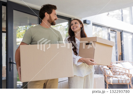 Couple carrying cardboard boxes while moving to a new house Couple carrying cardboard boxes while moving to a new house 132293780