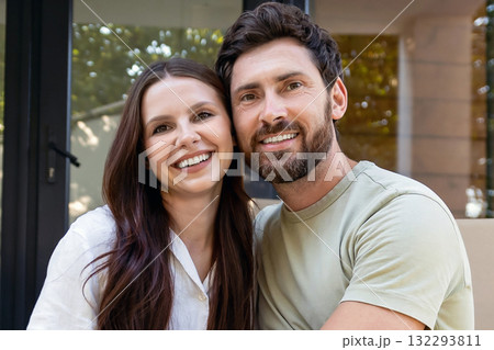 Happy couple sitting at the entrance of their new accommodation and looking contented 132293811