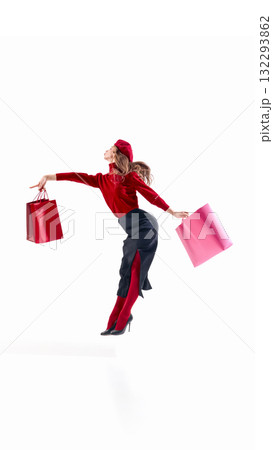 Elegant woman in red sweater and beret holding shopping bags in balanced fashion motion Elegant woman in red sweater and beret holding shopping bags in balanced fashion motion 132293862