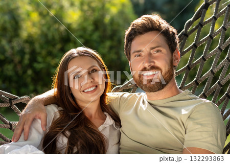 Cute smiling couple enjoying time together while sitting in hammock in the park Cute smiling couple enjoying time together while sitting in hammock in the park 132293863