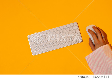 Minimal keyboard and mouse with hand on orange background 132294151