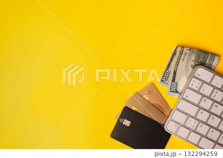 Credit cards and cash with computer keyboard on bright yellow background for online payments 132294259