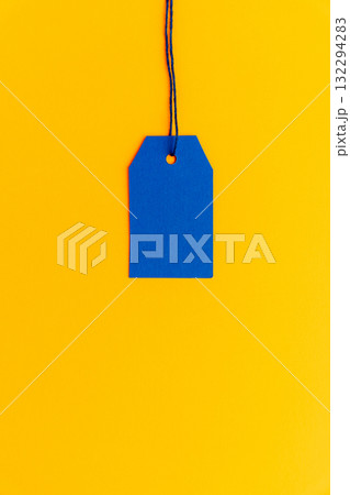 Blue price tag on yellow background minimal top view Blue price tag on yellow background minimal top view 132294283